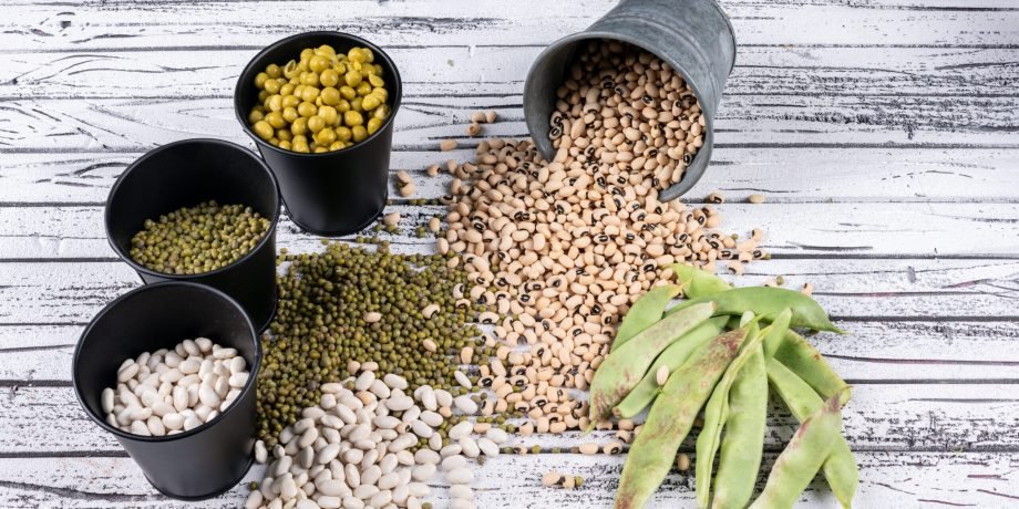 High angle view different types of peas and beans in buckets and aside on gray wooden background. horizontal